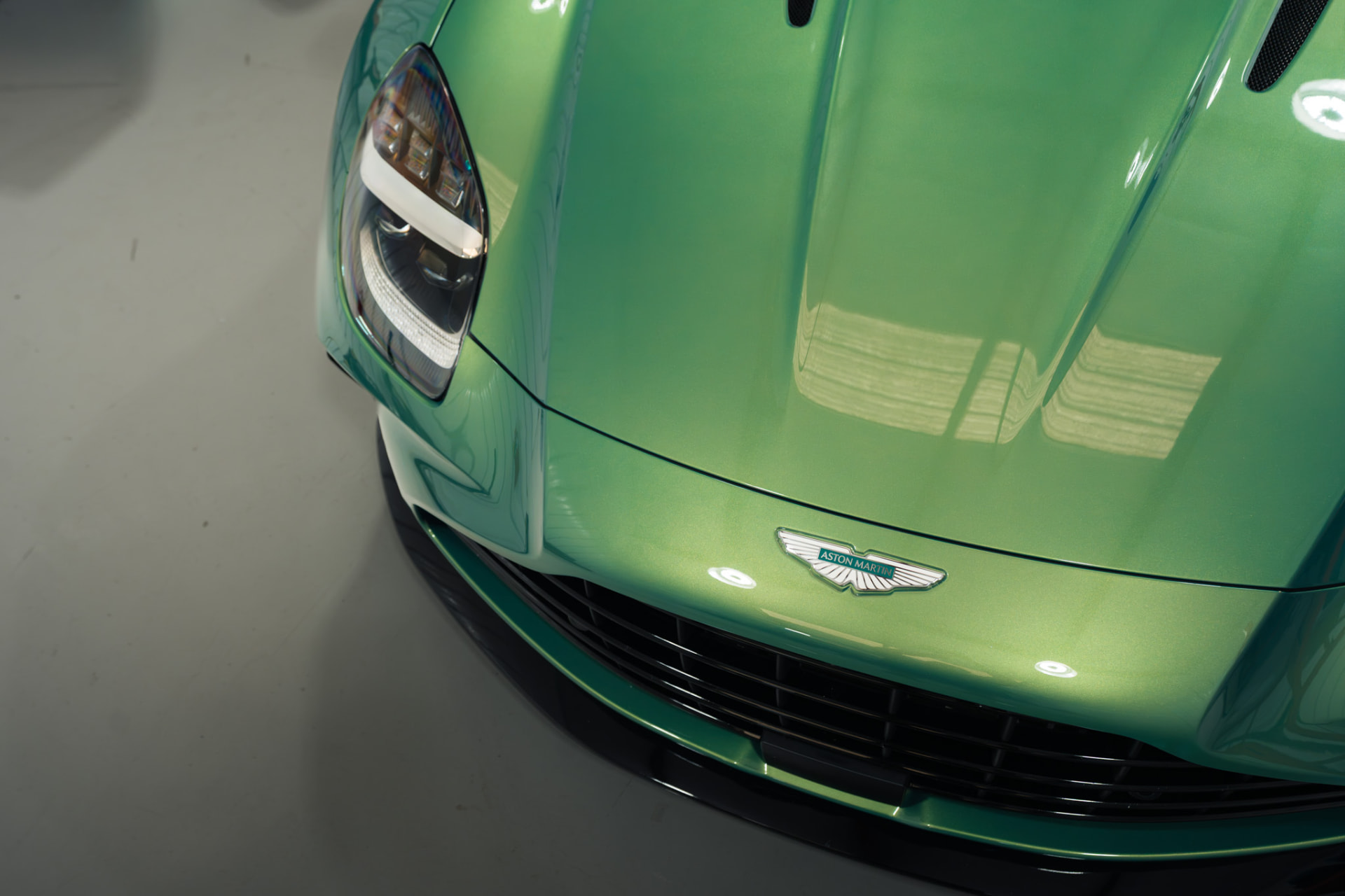 Close-up of a green Aston Martin hood and badge